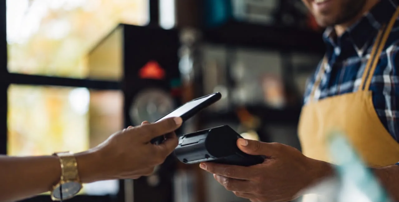 Customer paying by phone at a POS terminal